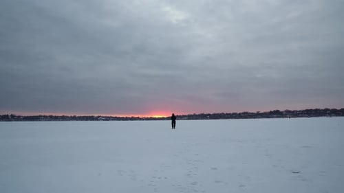 Man Walking Dog on Frozen Lake at Dusk