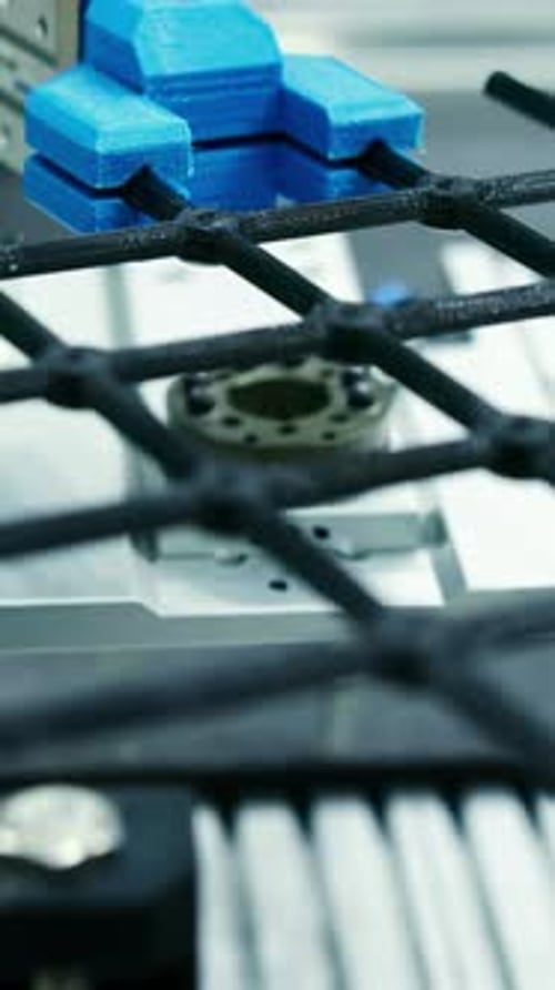 Bras robotique déplaçant un maillage en fibre de carbone sur les supports de la chaîne de production