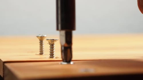 Screwdriver Tightening Screws into Wood Close Up