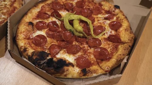 rotating shot of delicious Italian pizzas delivered in boxes on the table, pizza with burned crust