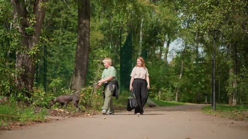 Adult And Kid Explore Shaded Forest With Playful Dog Nearby Guardian And Young One Stroll Along
