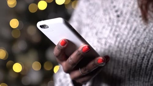 Tan cerca como una mujer negra usando un teléfono móvil, mandando mensajes con las manos de un smartphone.