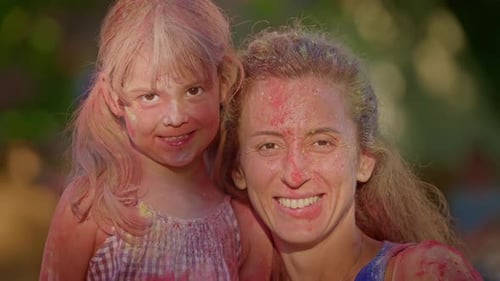 Smiling Child and Adult Covered in Colorful Powder