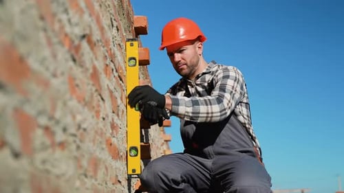 Bauarbeiter verwendet Nivellierwerkzeug zum Ausrichten der Ziegelmauer