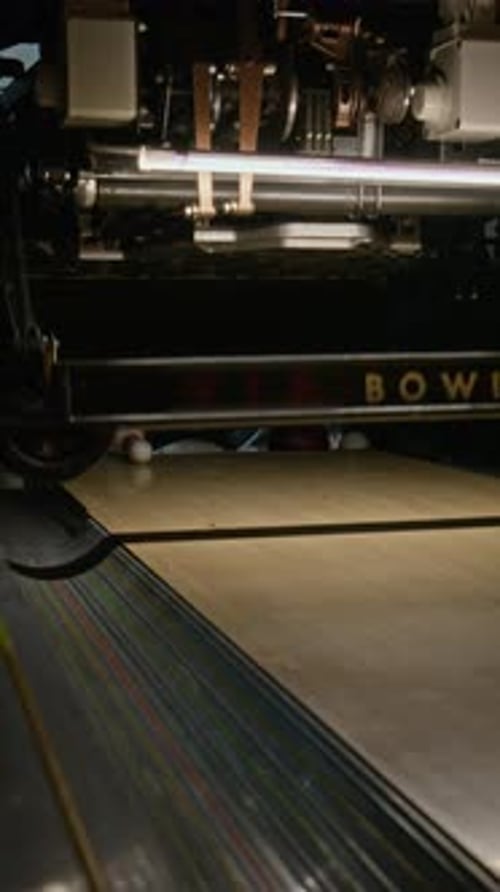 Bowlingkugel rollt auf einer Holzbahn und trifft Kegel für einen Schlag