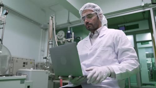 Man in Lab Coat Working on Laptop in Lab