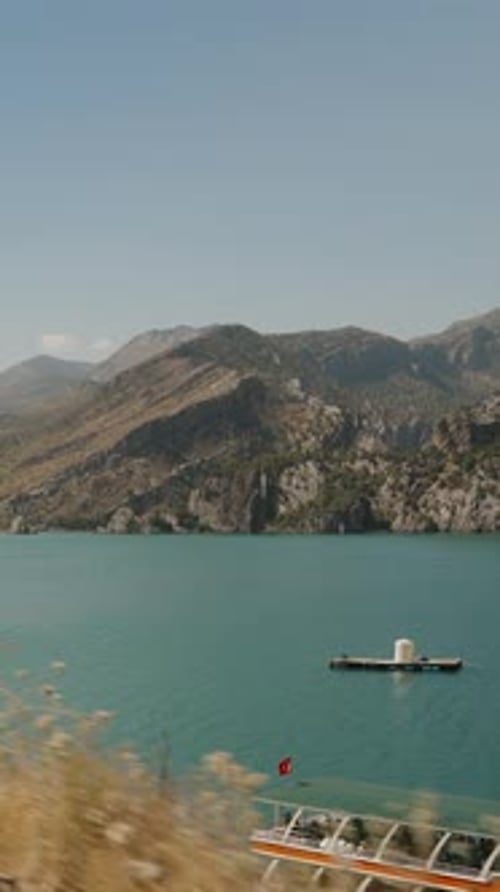 Vidéo verticale. Lac tranquille entouré de montagnes majestueuses, bateaux flottant doucement, capturés
.