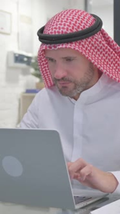Man in Keffiyeh Working on Laptop in Office