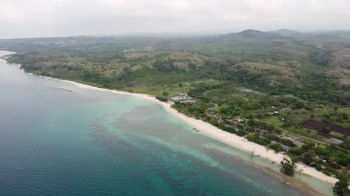Aerial view of tropical beach and sea water with small waves close to mountains.