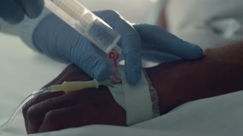 Doctor Putting Patient IV Doing Injection Closeup. Hospital Intensive Care Unit. Unrecognized