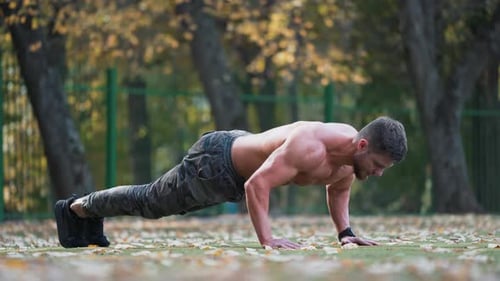 Deportista haciendo flexiones de brazos al aire libre. Hombre de fitness sin camisa haciendo flexiones en el suelo.