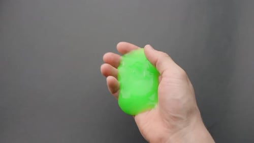 Close-up of green slime oozing through fingers in a fun and oddly satisfying moment