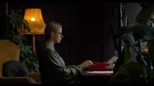 woman in a green shirt sits at a table in her cozy home, typing a novel on a vintage typewriter