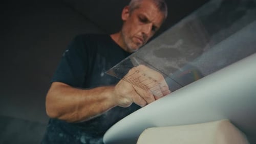 Surf factory. Adult male shaper creates the surfing board on the factory
