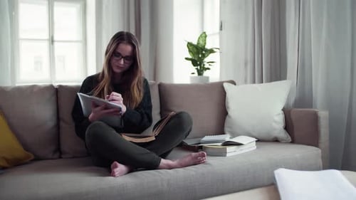 Woman Studying and Writing on Sofa Indoors