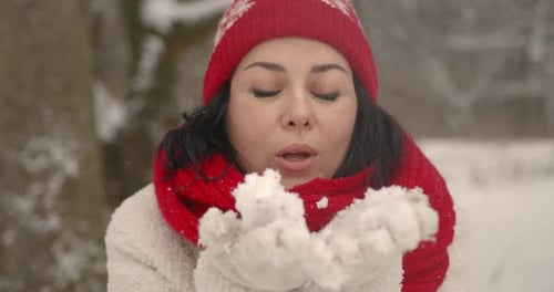 Woman blowing snow in winter landscape