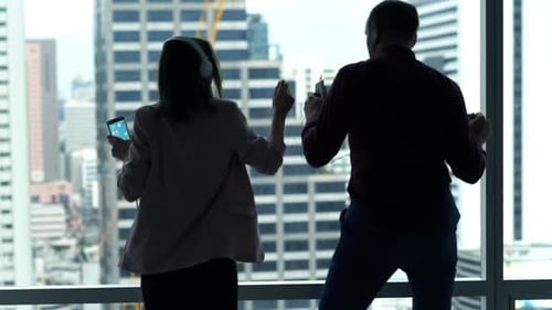 Businesspeople Listening to Music and Dancing by Window in Office Apartment