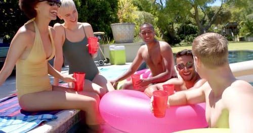 Happy diverse friends drinking drinks at pool party in summer