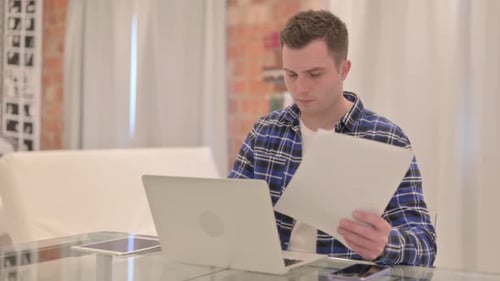 Adult working with laptop and document indoors