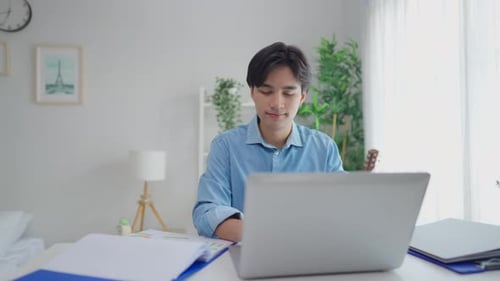 Smiling Man Using Laptop at Bright Home Desk