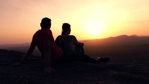 Silhouette Of Couple Admire Sunset And Landscape Standing On Hill