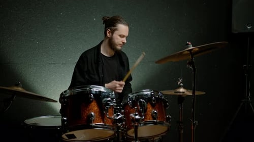 a young male drummer plays a drum kit in a recording studio at a professional musician's rehearsal