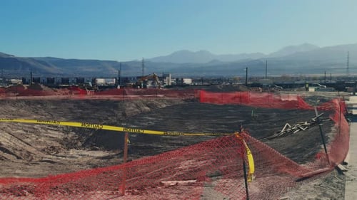 Amplio plano estático de una excavación de construcción con cinta de precaución y del horizonte de la montaña