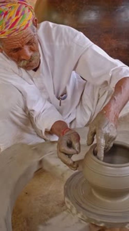 Potier professionnel lançant le tour de potier et façonnant un pot dans un atelier de poterie en Inde