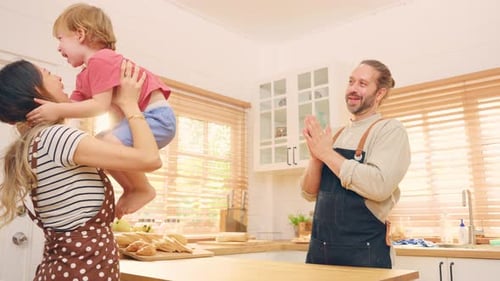 Mother Lifts Laughing Child in Bright Kitchen