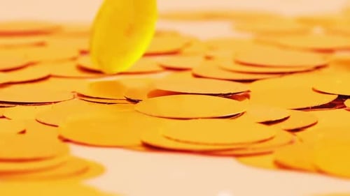 Falling confetti on a peach background. Slow motion.