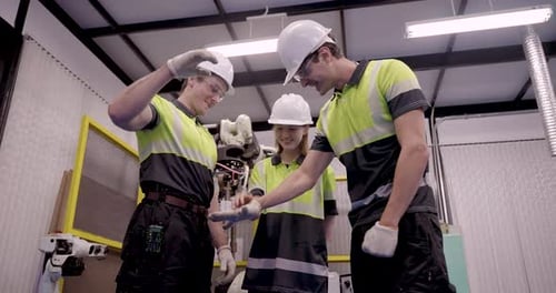 Ein Team von männlichen und weiblichen Ingenieuren in Sicherheitsuniform arbeitet während der Robotikausbildung in Smart zusammen