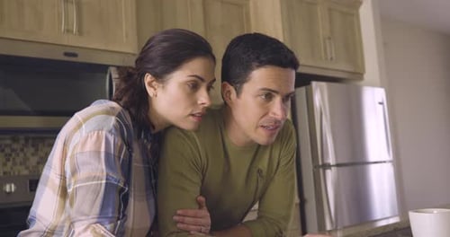 Young Couple Looking at a Laptop in Kitchen