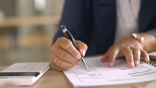 Woman Writes on Paper with Calculator Nearby