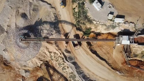 large Quarry during work hours with Stone sorting conveyor belts and an open pit mine.