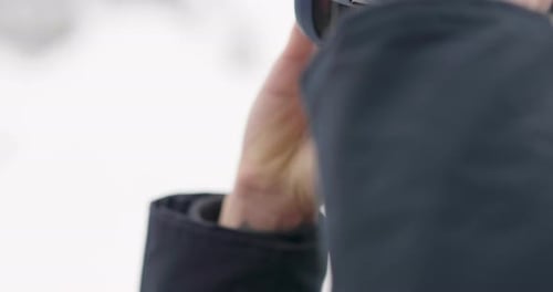 Close-up of a smiling skier's face on a vacation in the mountains, peering over the ski slopes. Co