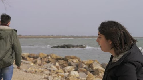 junges Paar streitet sich am Strand, Mann küsst Frau, er ist weggegangen