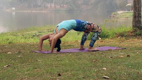 Femme asiatique pratiquant le yoga à Urdhva Dhanurasana ou Chakra-asana ou Wheel Pose dans un parc extérieur.