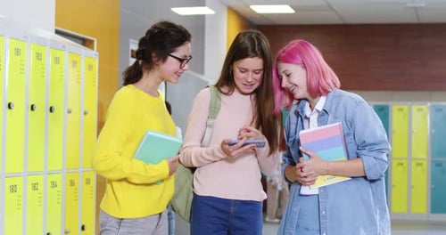 Three School Age Friends Using Smartphone in Corridor During Break Caucasian Smiling Schoolgirls