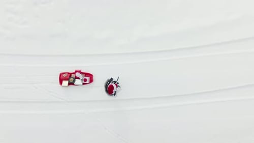 Femme en costume de père Noël marchant dans la neige blanche avec un traîneau rouge avec des coffrets cadeaux