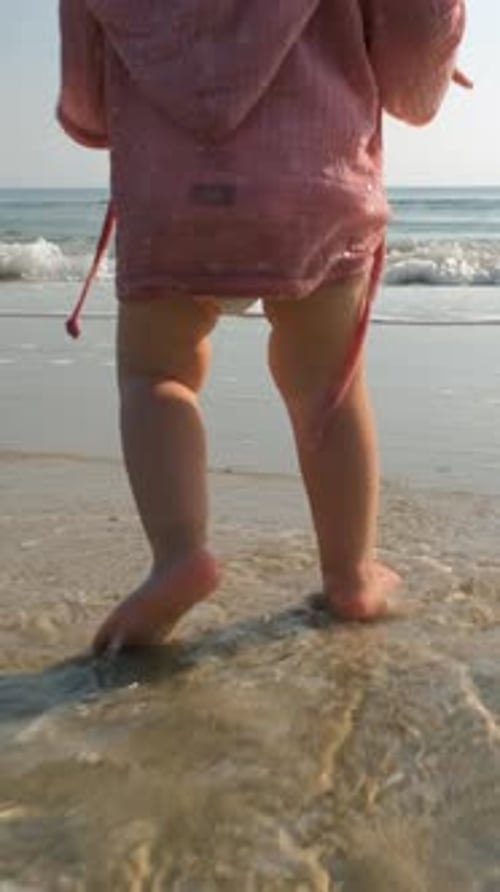 Cute Baby Girl Walks with Mom on Beach Shoreline