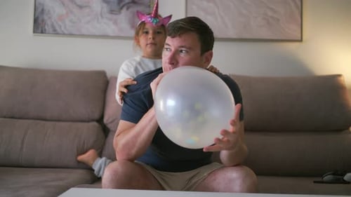 Dad Inflates Balloon with Little Girl