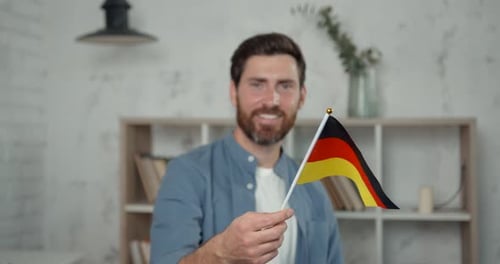 Glücklicher kaukasischer Lehrer mit Bart hält Flagge von Deutschland