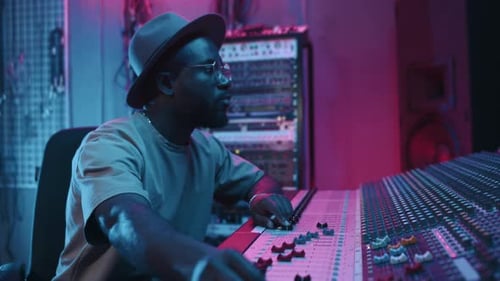 Young Male Sound Engineer Adjusting Noise Level while Recording New Music