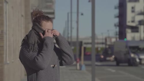 Man wearing scarf standing on the street breathing deeply. Person in an urban city.