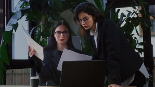 Joven empresaria con gafas analiza con su colega el plan estratégico descrito en un informe