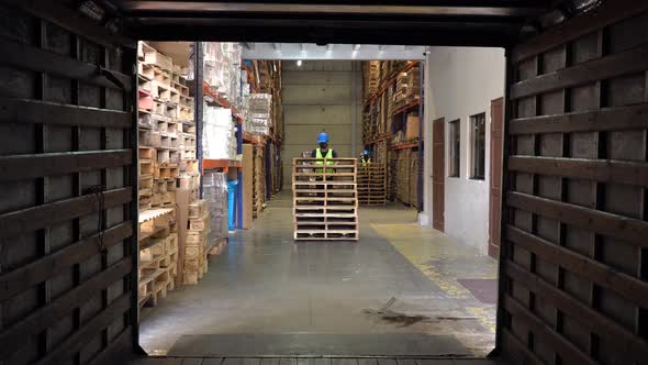 A worker inside a storage area of a warehouse, storing a stack of ...