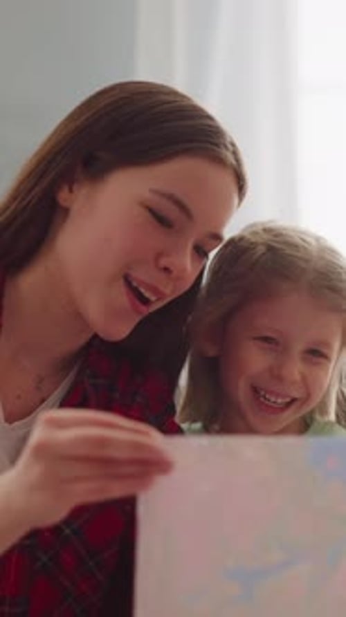 Joyful Teenage Girl and Sister Look at Painting in Apartment