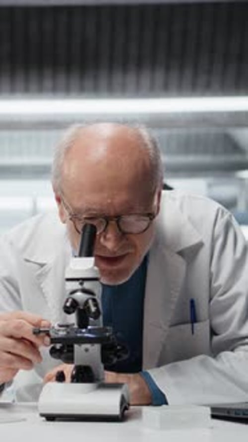 Senior Scientist Looking Through Microscope in Lab