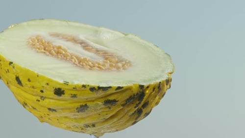 La moitié d'un melon jaune avec des os, des gouttes d'eau en coulent, sur un ciel bleu, gros plan