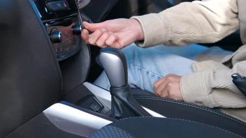 A Woman Turns on the Radio in Her Car